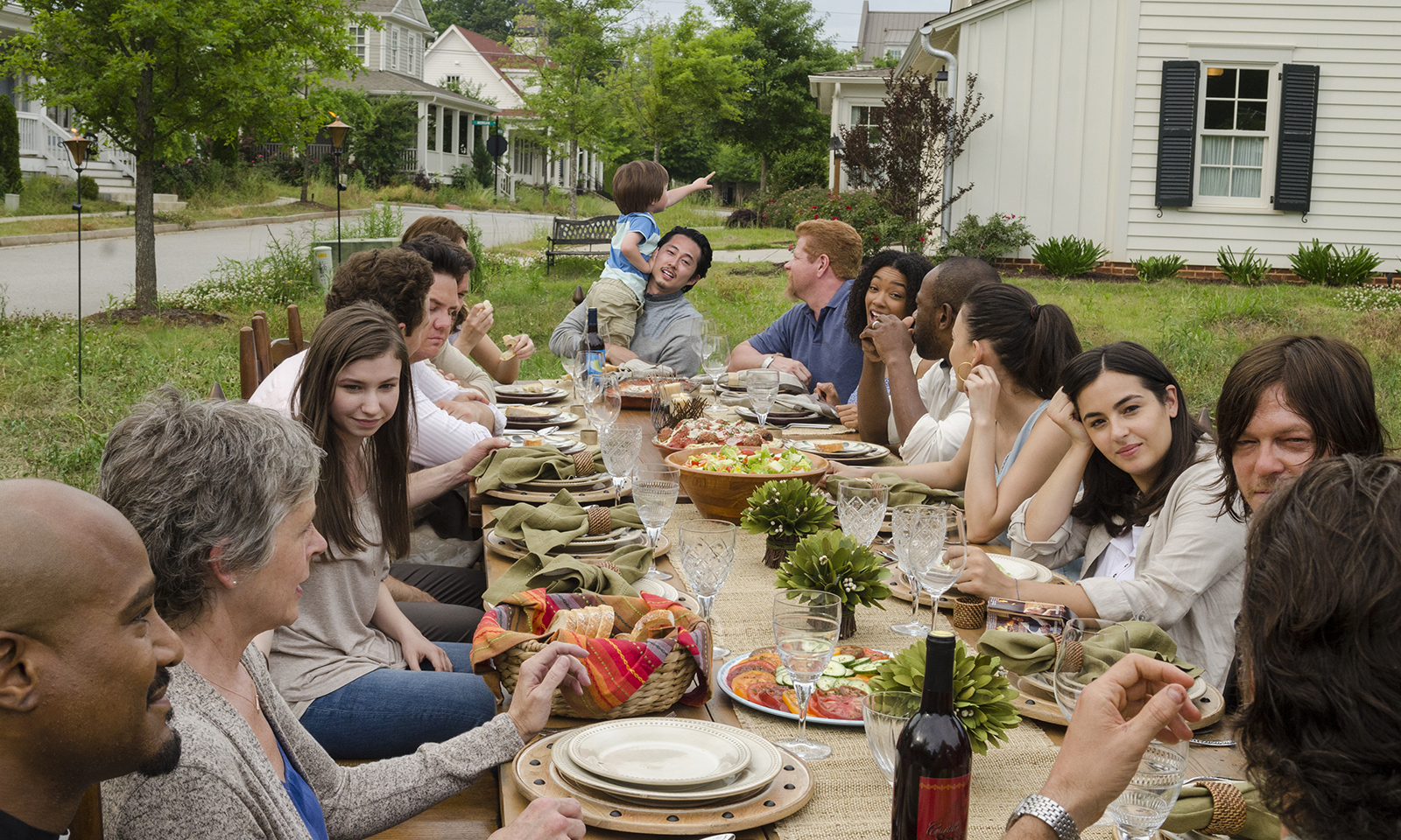 Personagens reunidos em uma mesa cheia de comida em um futuro alternativo de The Walking Dead