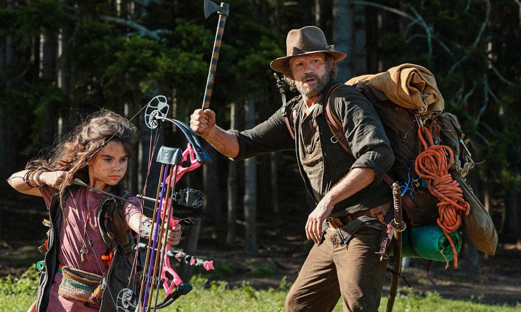 Ariana Greenblatt e Michael Rooker armados em imagem promocional do filme Amor e Monstros