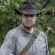Josh McDermitt como Eugene Porter segurando sua arma em cena da 10ª temporada de The Walking Dead.