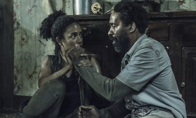 Connie e Virgil sentados no chão da casa e tocando um na mão do outro no episódio 6 da 11ª temporada de The Walking Dead.