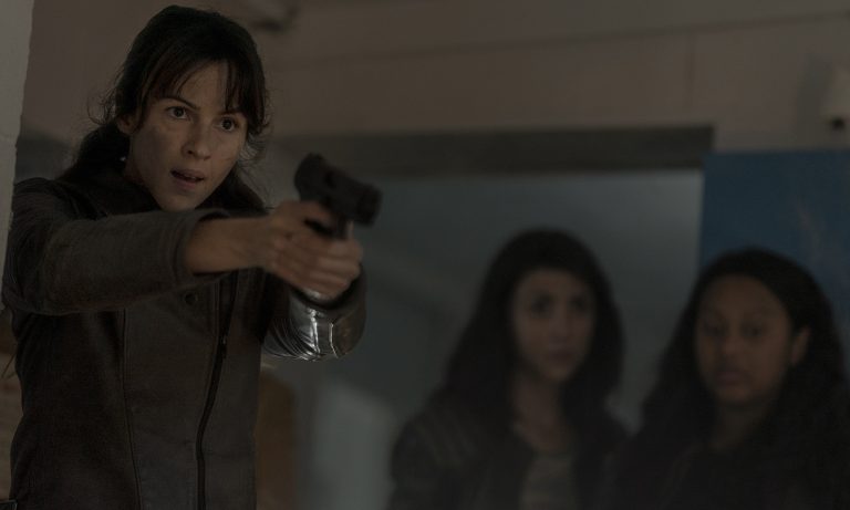 Huck apontando uma arma enquanto Iris e Hope observam no episódio 7 da 1ª temporada de The Walking Dead: World Beyond.