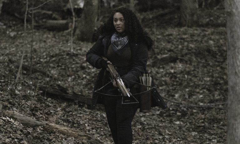 Iris segurando sua crossbow na floresta no episódio 1 da 2ª temporada de The Walking Dead: World Beyond.