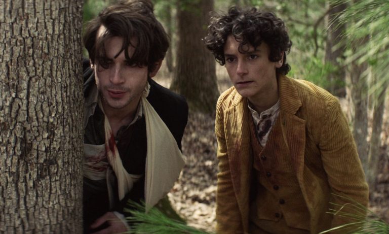 Elton e Percy se escondendo atrás de uma árvore enquanto fogem de alguém no episódio 3 da 2ª temporada de The Walking Dead: World Beyond.