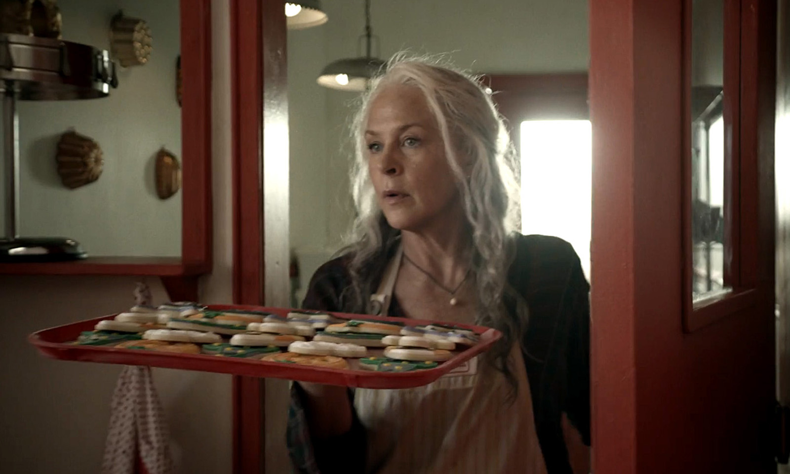 Carol segurando alguns biscoitos e observando em cena da 11ª temporada de The Walking Dead.