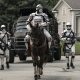 Dois soldados de Commonwealth a cavalo e dois andando em Alexandria no episódio 12 da 11ª temporada de The Walking Dead.