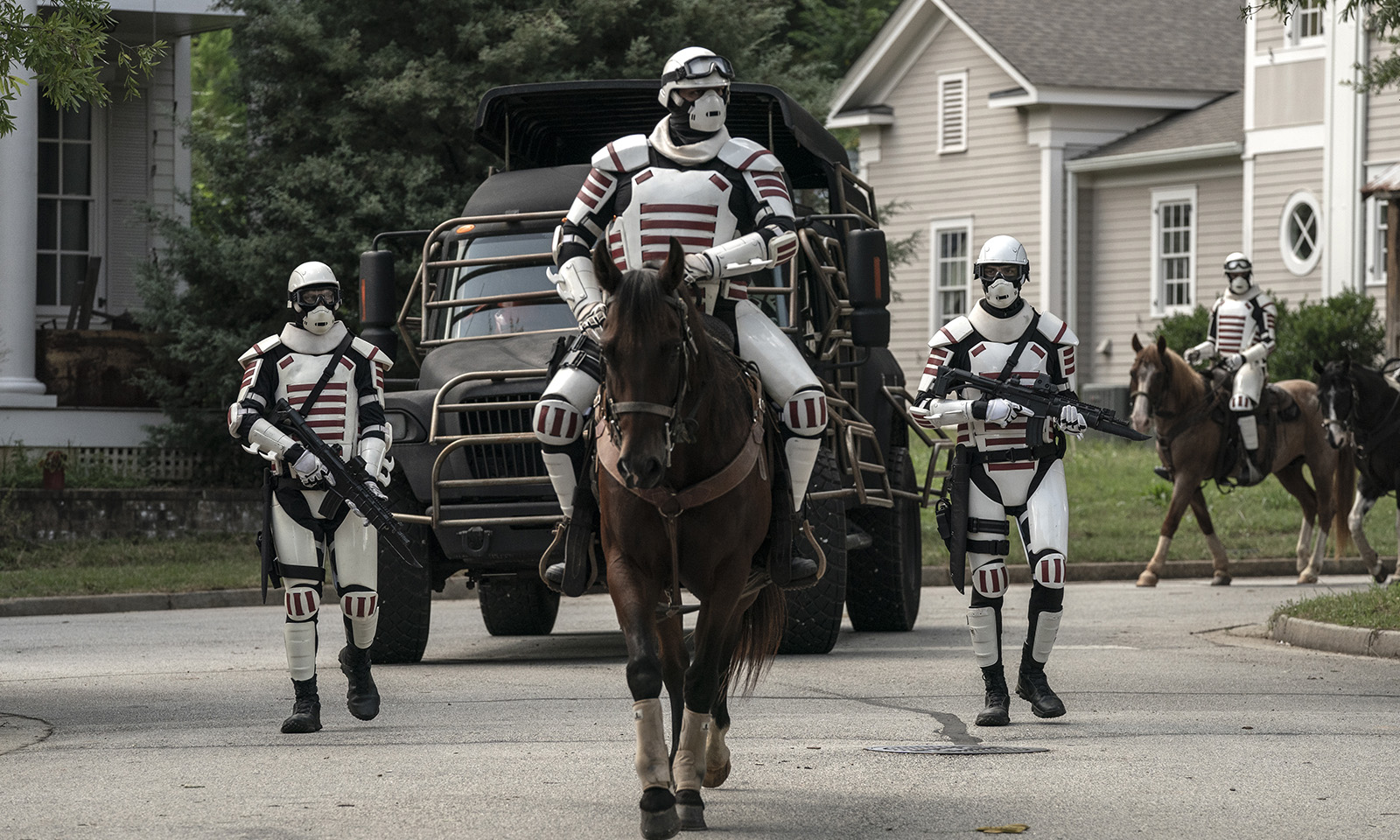 Dois soldados de Commonwealth a cavalo e dois andando em Alexandria no episódio 12 da 11ª temporada de The Walking Dead.