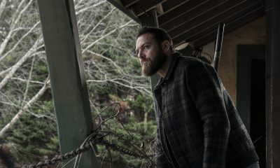Aaron em um lugar desconhecido observando algo ou alguém em cena do episódio 19 da 11ª temporada de The Walking Dead.