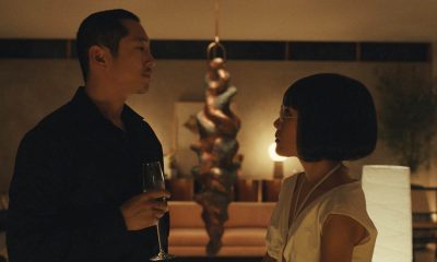 Steven Yeun como Danny Cho segurando uma taça e encarando Ali Wong como Amy Lau em cena da série Beef, da Netflix.