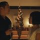 Steven Yeun como Danny Cho segurando uma taça e encarando Ali Wong como Amy Lau em cena da série Beef, da Netflix.