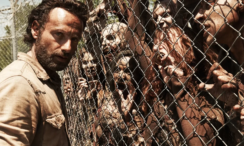 Imagem promocional com Rick na prisão e os zumbis na cerca na 4ª temporada de The Walking Dead.