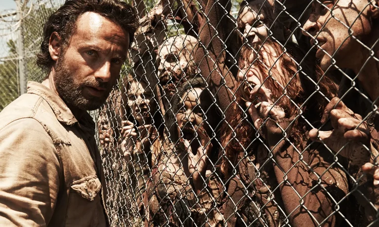 Imagem promocional com Rick na prisão e os zumbis na cerca na 4ª temporada de The Walking Dead.