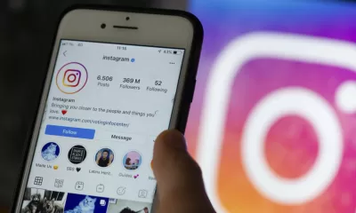 Imagem de um celular logado no Instagram com a logo da rede social ao fundo.