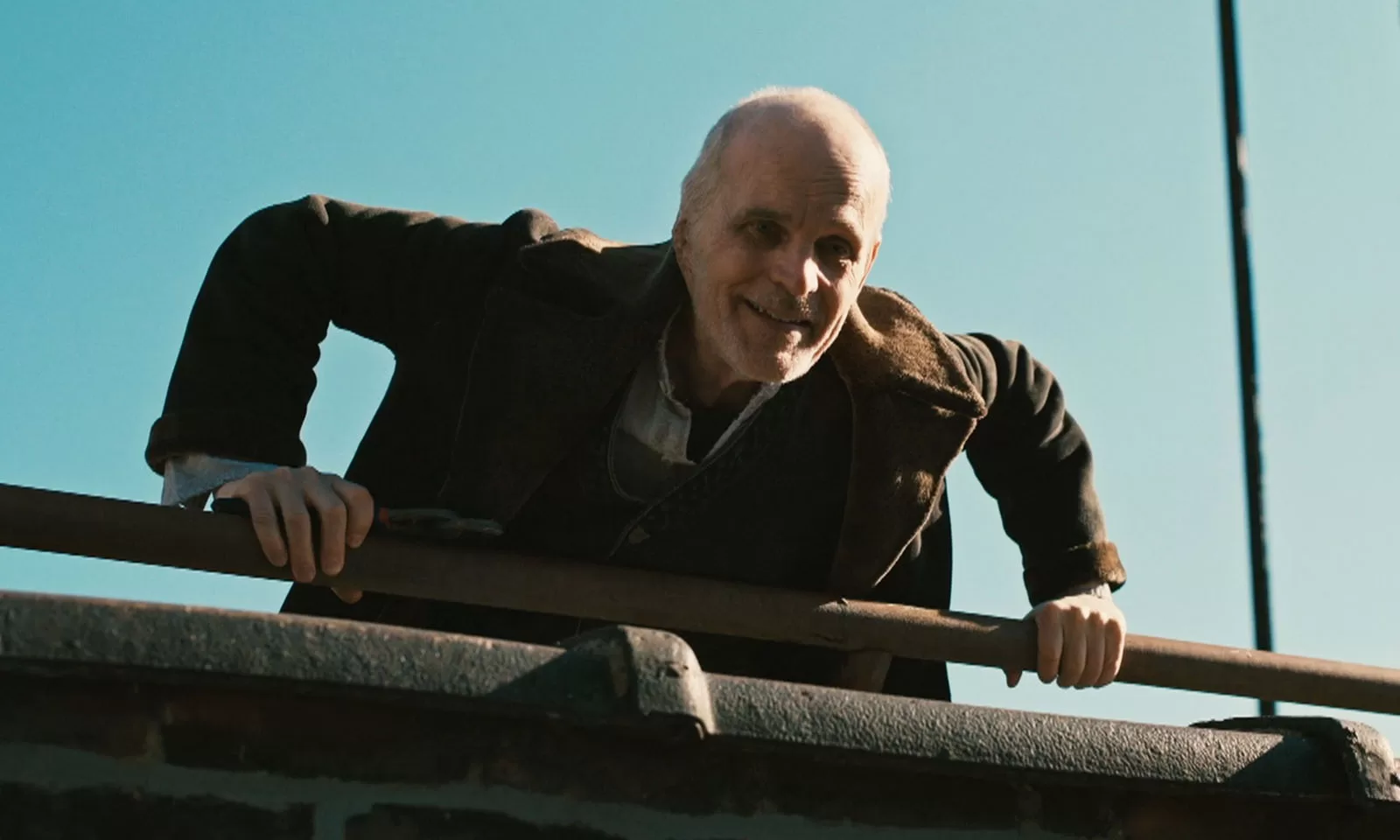 O Croata sorrindo após derrubar seu prisioneiro de cima do prédio em cena do episódio 1 da 1ª temporada de The Walking Dead: Dead City.