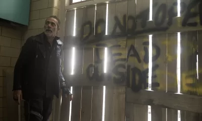 Negan olhando para algo ou alguém com uma porta ao fundo com a frase "Não abra, mortos do lado de fora" em cena do episódio 5 da 1ª temporada de The Walking Dead: Dead City.