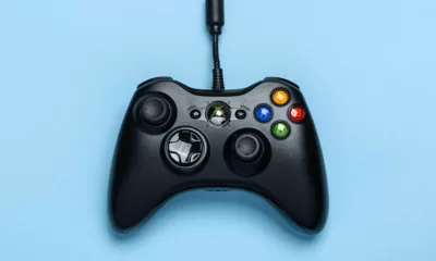 Imagem de um controle preto do XBOX One com fundo azul.