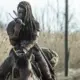 Michonne falando com alguém pelo rádio e montada em seu cavalo em cena do Episódio 2 de The Walking Dead: The Ones Who Live.