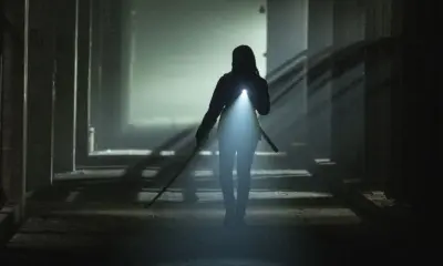 Michonne com sua katana e utilizando uma lanterna em um local desconhecido e escuro em cena do Episódio 3 de The Walking Dead: The Ones Who Live.