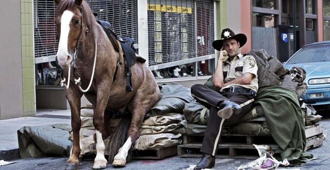 Rick Grimes sentado ao lado de seu cavalo durante os bastidores do primeiro episódio de The Walking Dead.