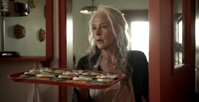 Carol segurando alguns biscoitos e observando em cena da 11ª temporada de The Walking Dead.