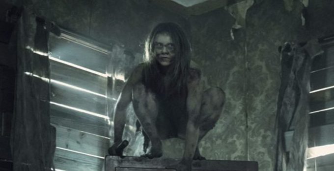 Mulher selvagem segurando algo em cima de alguma coisa em casa abandonada no episódio 6 da 11ª temporada de The Walking Dead.