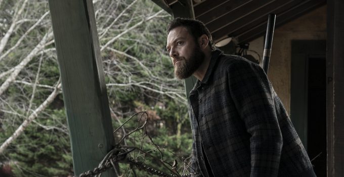 Aaron em um lugar desconhecido observando algo ou alguém em cena do episódio 19 da 11ª temporada de The Walking Dead.