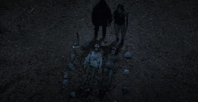 Elton e Asha de mãos dadas e fazendo uma oração sob 2 zumbis no chão com flores em seus olhos no episódio 6 da 2ª temporada de The Walking Dead: World Beyond.