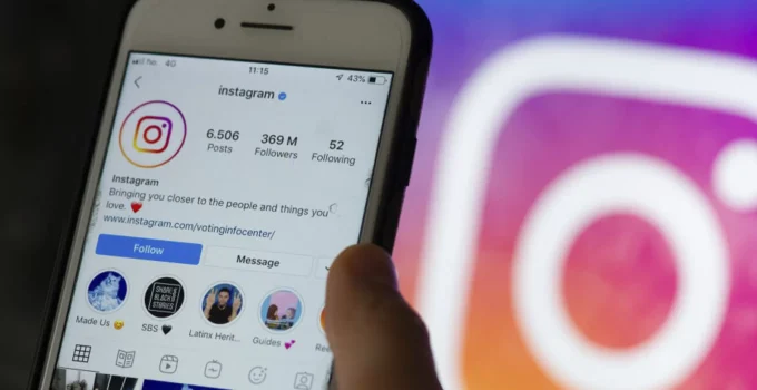 Imagem de um celular logado no Instagram com a logo da rede social ao fundo.